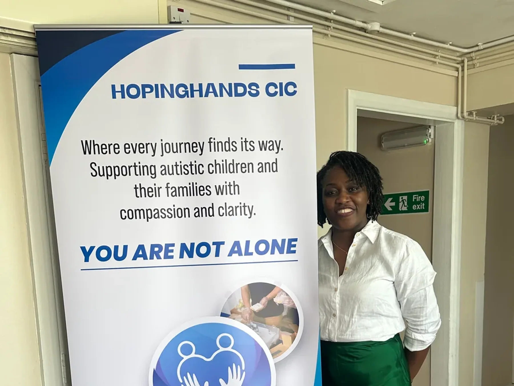 A HopingHands team member beside the You Are Not Alone message